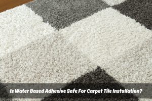 Close-up of a gray and white checkered carpet tile with a small amount of white carpet tile adhesive spread in the corner