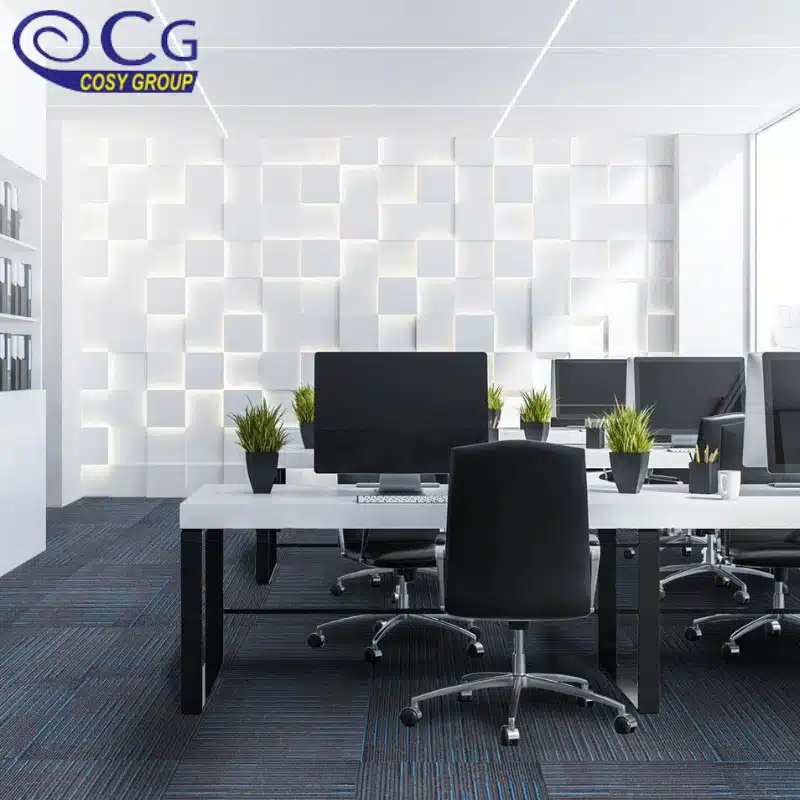A modern office space with a white wall, black office chairs, and blue carpet tiles.