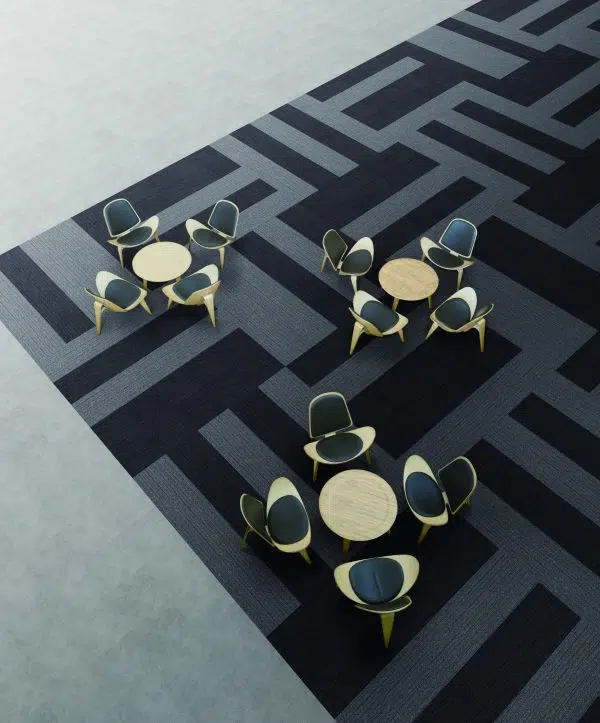 An aerial view of a modern office space with patterned carpet tiles and minimalist furniture.