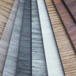 A collection of laminate flooring samples in various wood tones and finishes.