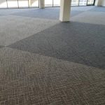 An office floor with patterned carpet tiles in a checkerboard design, creating a dynamic effect.