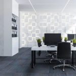 A modern office space with blue and black carpet tiles, sleek white desks, and a decorative wall.