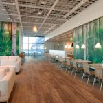 A spacious café with wood-look vinyl flooring, comfortable seating, and large windows with scenic views.